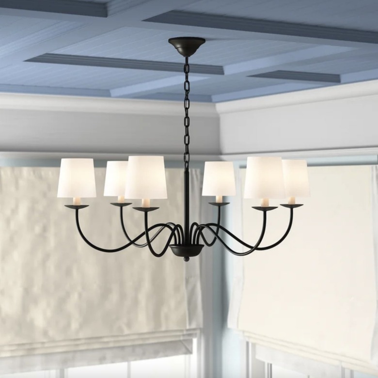 6-light black chandelier with white lamp shades in a living room with a blue ceiling.