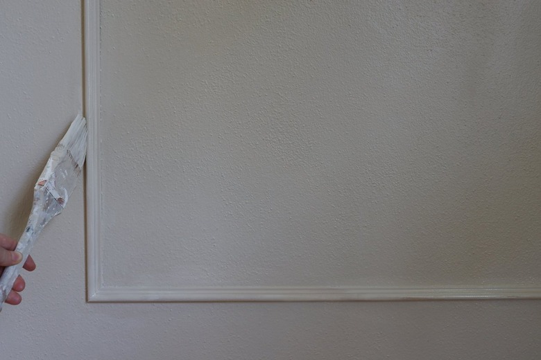 Painting wall molding with a paintbrush and taupe paint
