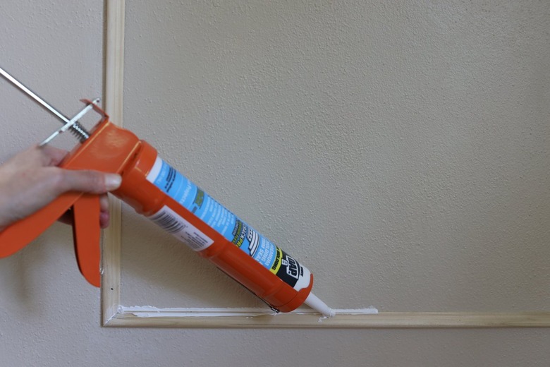 Applying caulk to the inner edge of the wall molding