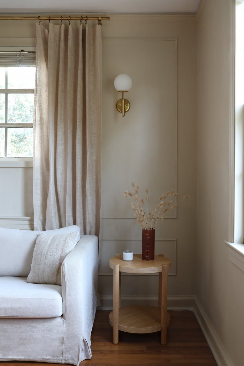 a globe sconce hangs on a taupe wall with wall moldings