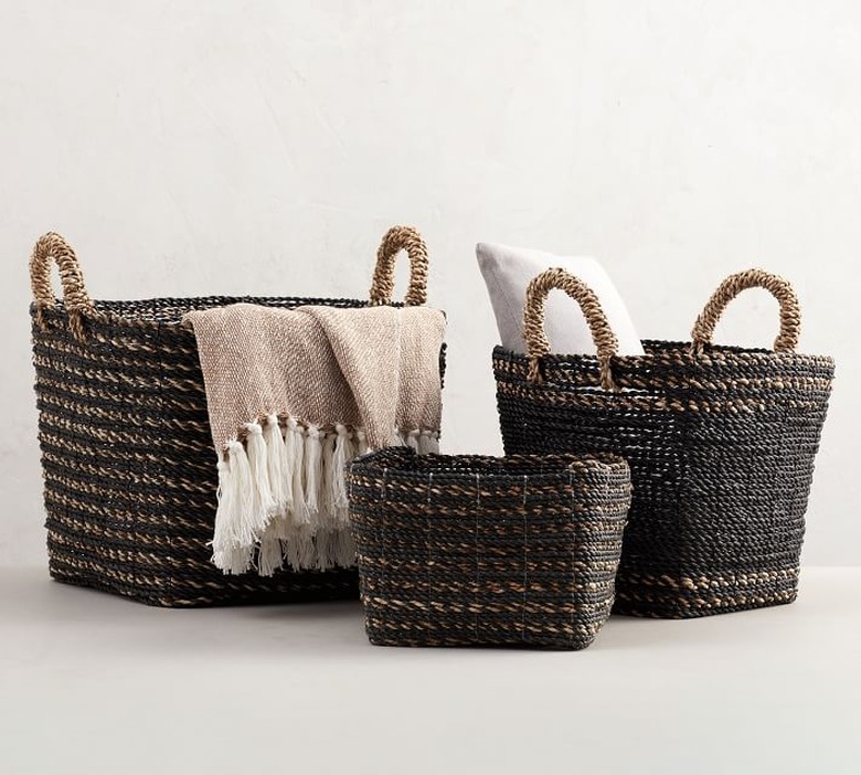 Handwoven black storage containers holding a pillow and throw blanket