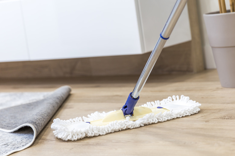 Modern white mop being used for cleaning a wooden floor