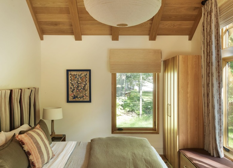 guest bedroom with pleated fabric headboard and wood plank ceiling