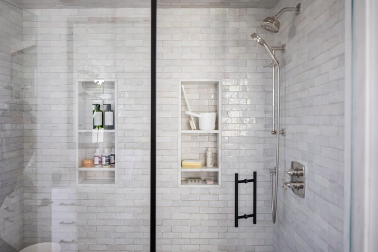 close up view of shower with subway tile walls and built-in storage