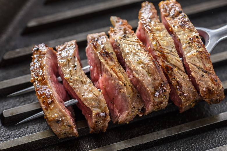 Slice of Grilled Steak with Seasoning on a Fork and Cast Iron Grill
