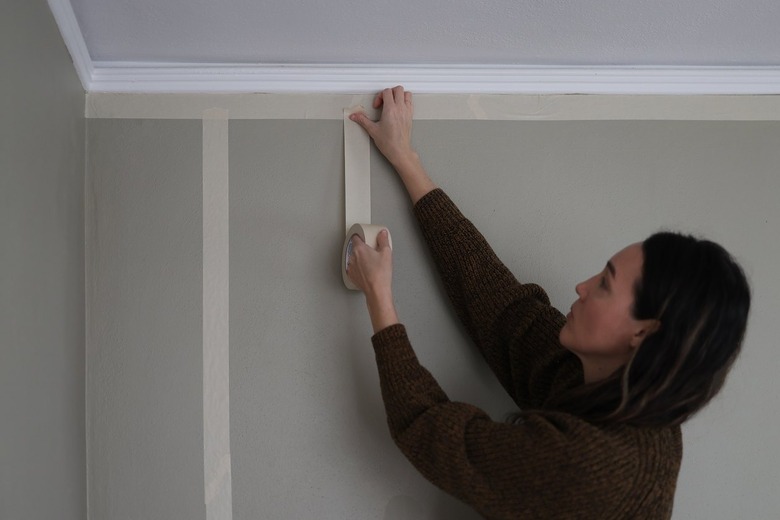 Attaching vertical strips of white painter's tape to wall