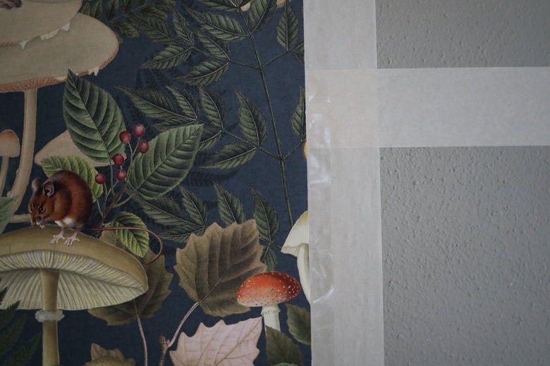 Green forest animal wallpaper attached to painter's tape grid