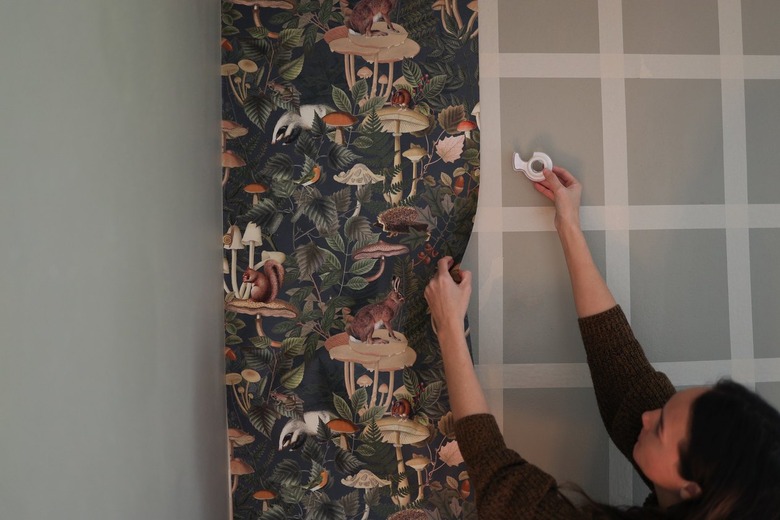 Green forest animal wallpaper attached to painter's tape grid
