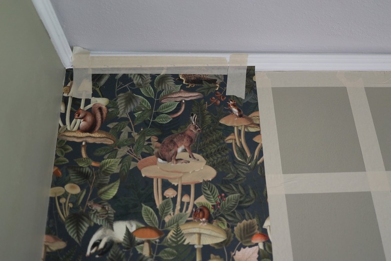 Green forest animal wallpaper attached to painter's tape grid