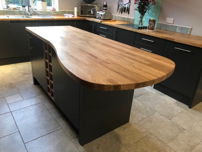 Custom kitchen island in blue with unique-shaped wood countertop in tile floor kitchen