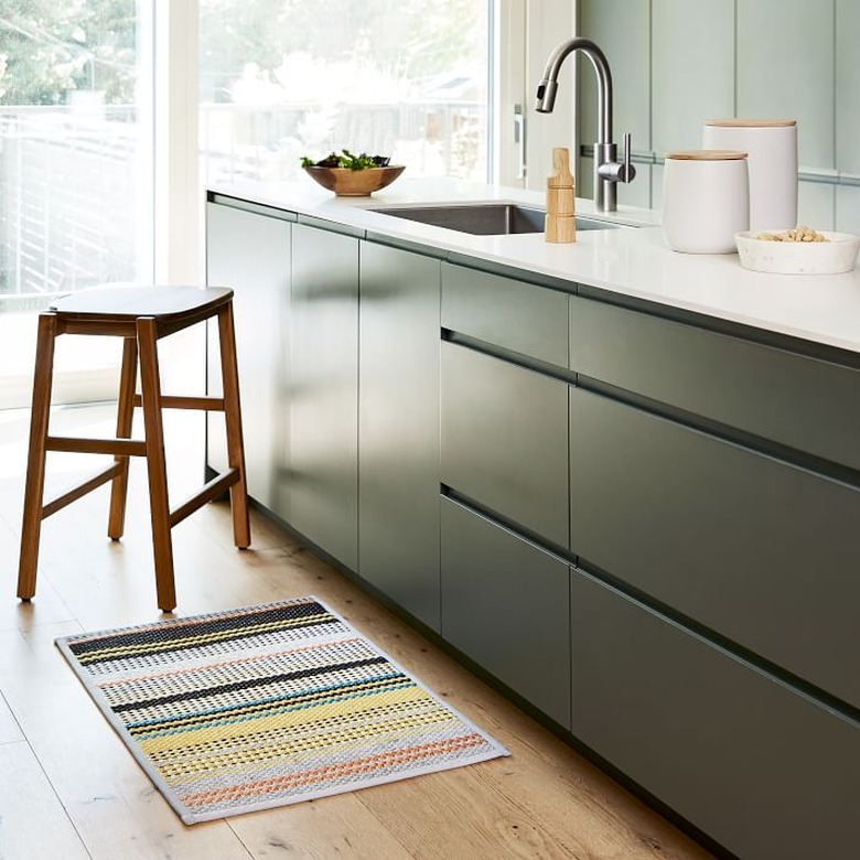 kitchen with black cabinets and colorful mat beneath the sink