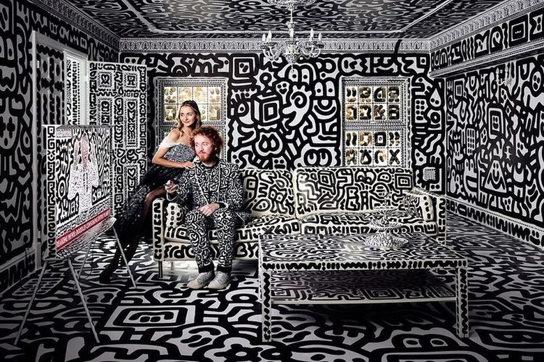 Sam Cox and his wife sitting on a doodled couch in a completely doodled living room.