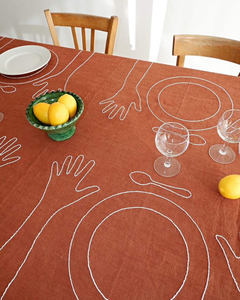 A burnt orange tablecloth on a table embroidered with plates