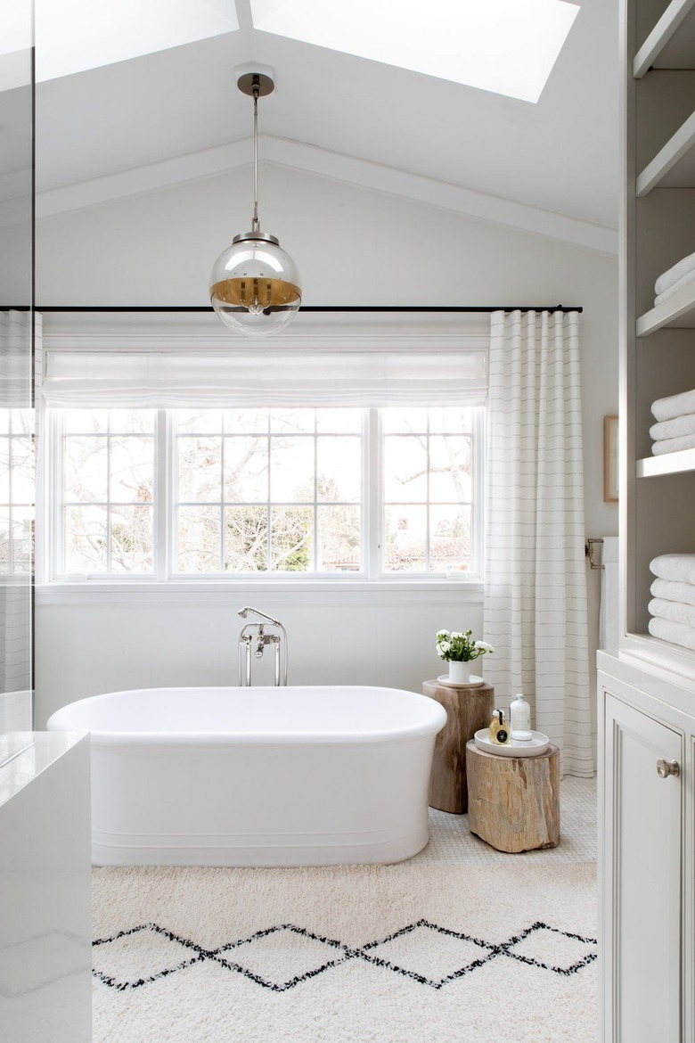 all white bathroom with glass and gold pendant light