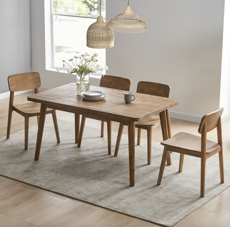 Image of a Scandi style dining table in a sparsely decorated room. The table sits on a beige rug