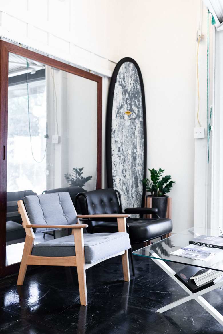 surfboard next to mirror and chairs in office space