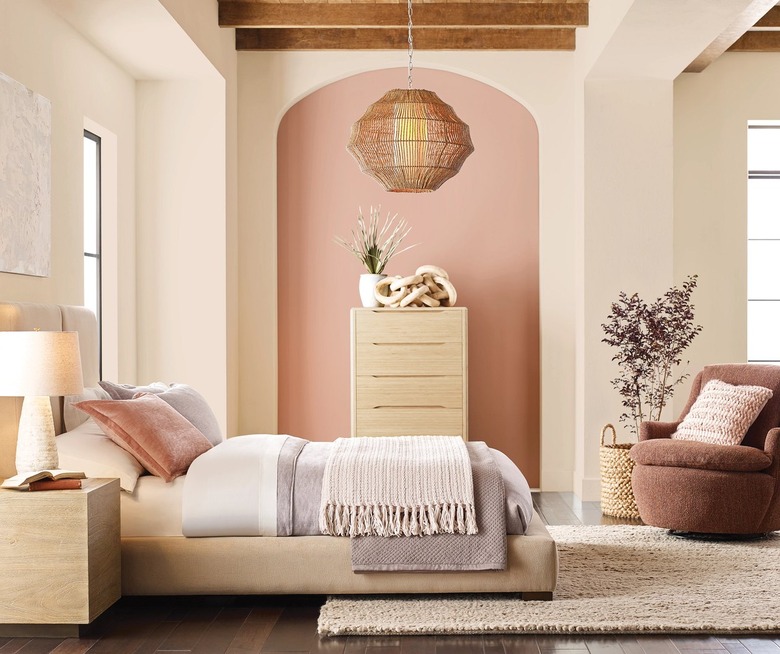 Pastel colored bed facing sideways in front of a beige and pink wall with a dresser