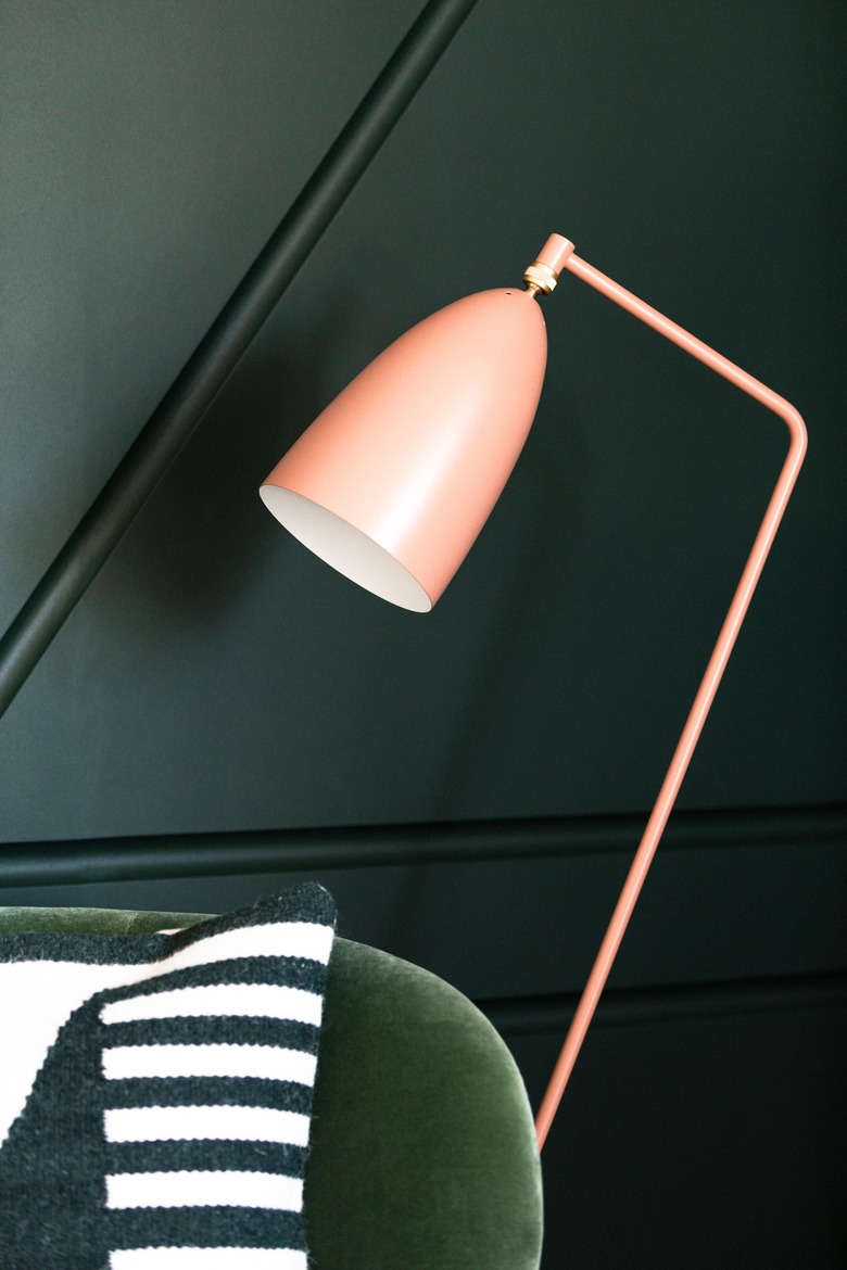 Gubi Grossman Gräshoppa Floor Lamp in Vintage Red next to green sofa and accent wall