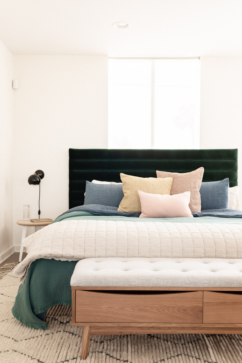 upholstered headboard in bedroom with bed bench and wallsconces