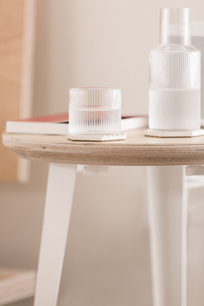 birch side table with white metal legs and a glass carafe with geometric coaster