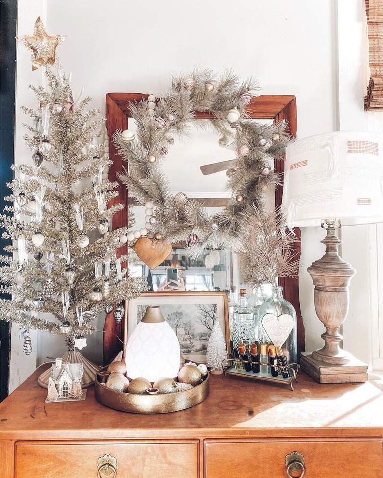 Top of a dresser with metallic gold and silver christmas decor on it