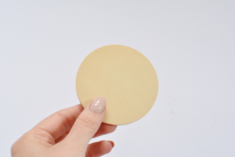 Hand holding wooden circle.