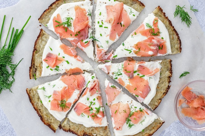 An aerial view of the Smoked Salmon Latke Pizza surrounded by fresh dill