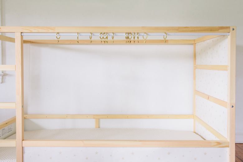 Tension rod and curtain rings hung across KURA bed