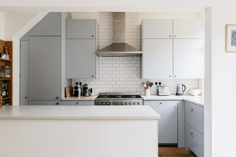 Subway tile backsplash in kitchen with light blue cabinets.