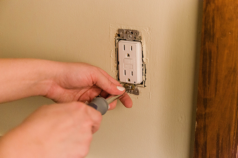 Push the outlet back inside the wall and screw it in place.
