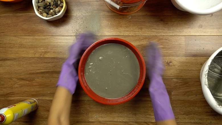 Agitating concrete mix to release bubbles for DIY tabletop concrete fire bowl.