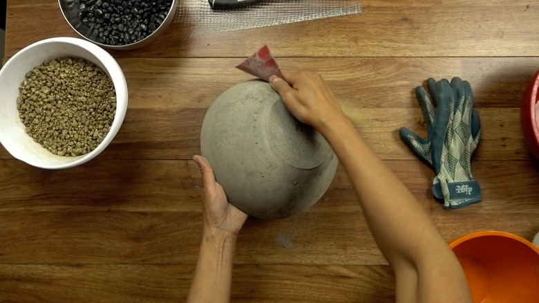 Sanding a newly-formed concrete bowl.