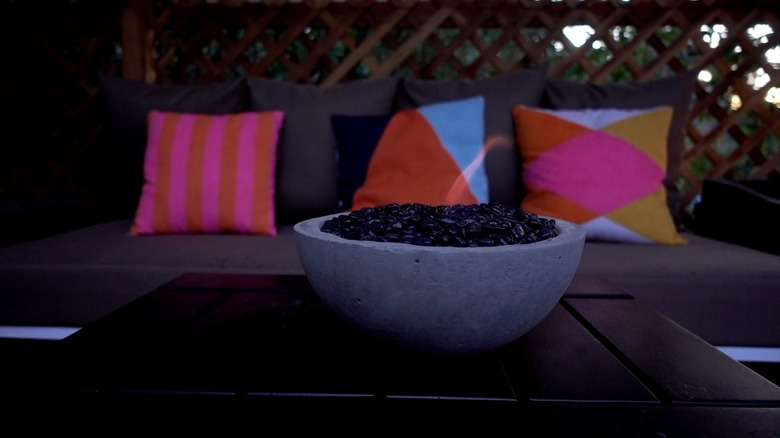 DIY tabletop concrete fire bowl on an outdoor coffee table in the evening.