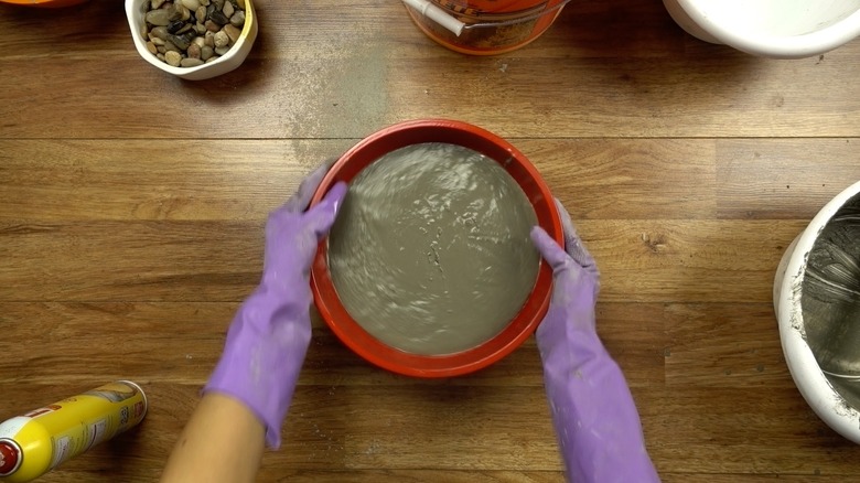 Agitating concrete to release bubbles for DIY tabletop concrete fire bowl.
