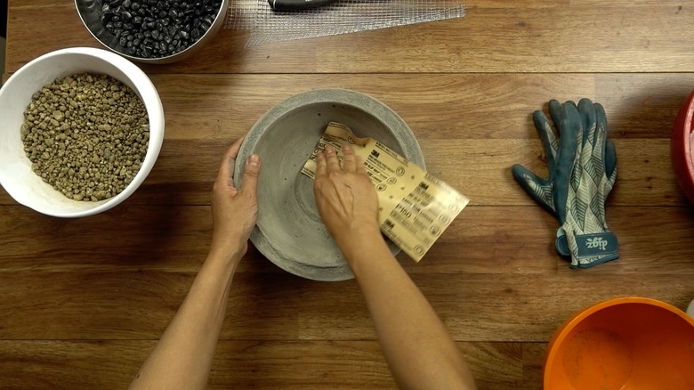 Sanding a newly-formed concrete bowl.