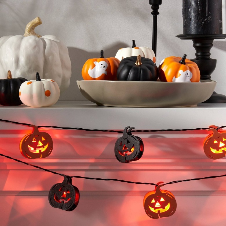 A matel with wood jack-o'-lantern lights hanging off of it. On the mantel