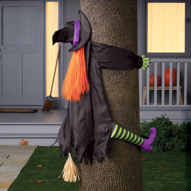A fake witch crashing into a tree. The witch has a black cloak