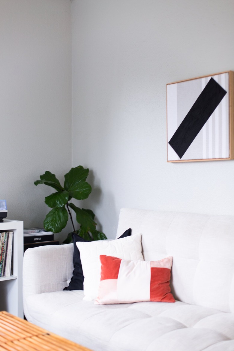 neutral sofa with orange and black throw pillows next to fiddle leaf fig