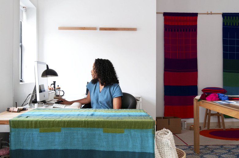 Hana Getachew Bolé Road Textiles sitting at desk surrounded by colorful patterned textiles