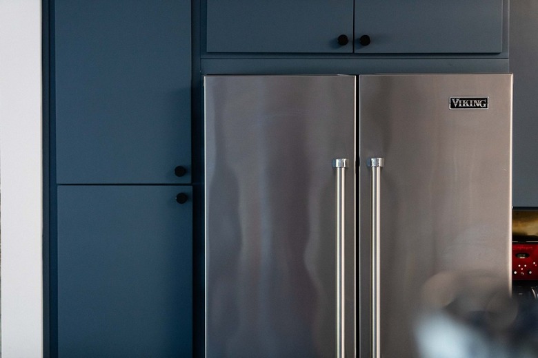 stainless steel refrigerator built into blue kitchen cabinets