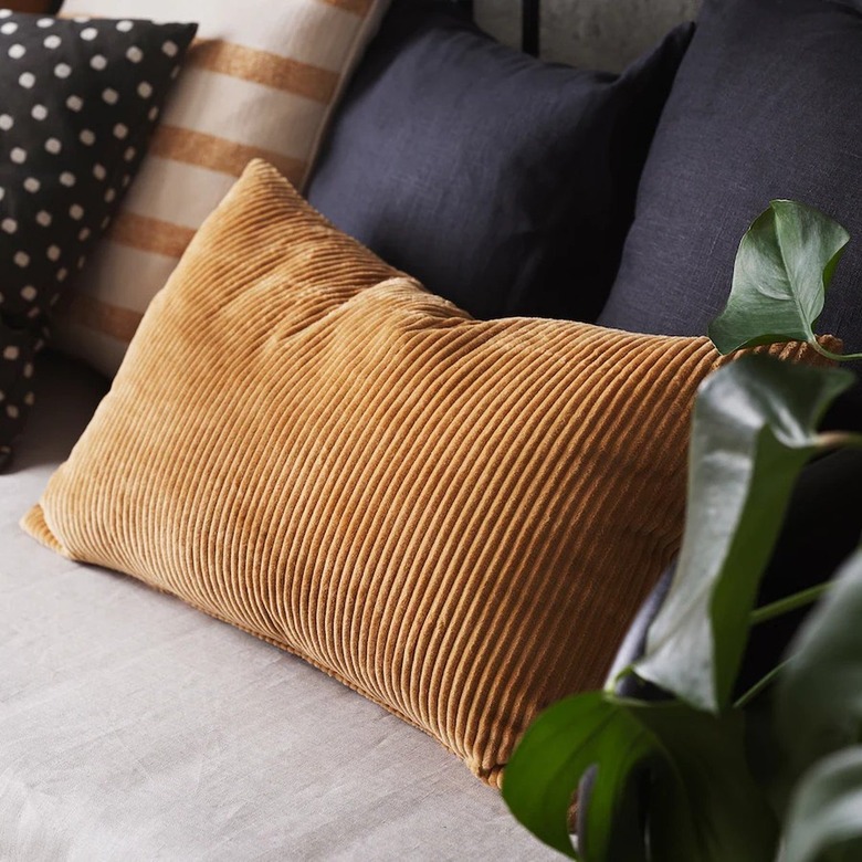 A rectangular pillow with a brown corduroy cover on a couch