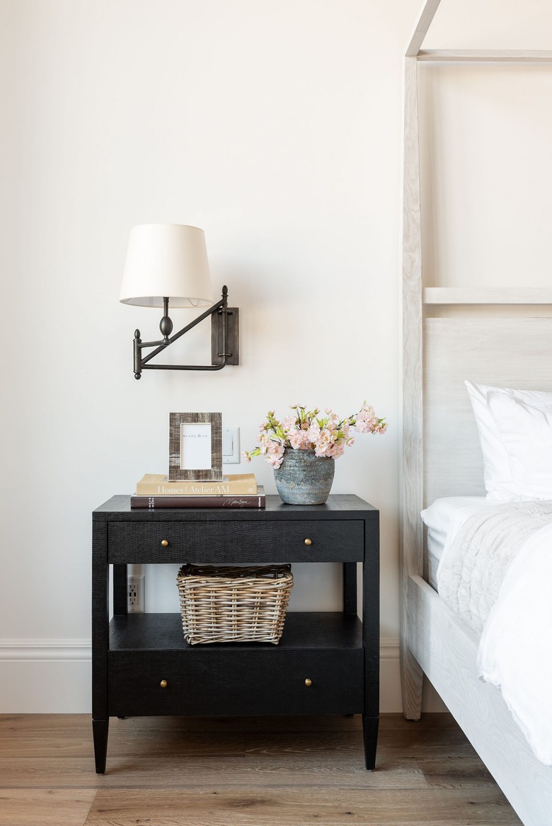 White bedroom with bronze lamp attached to wall