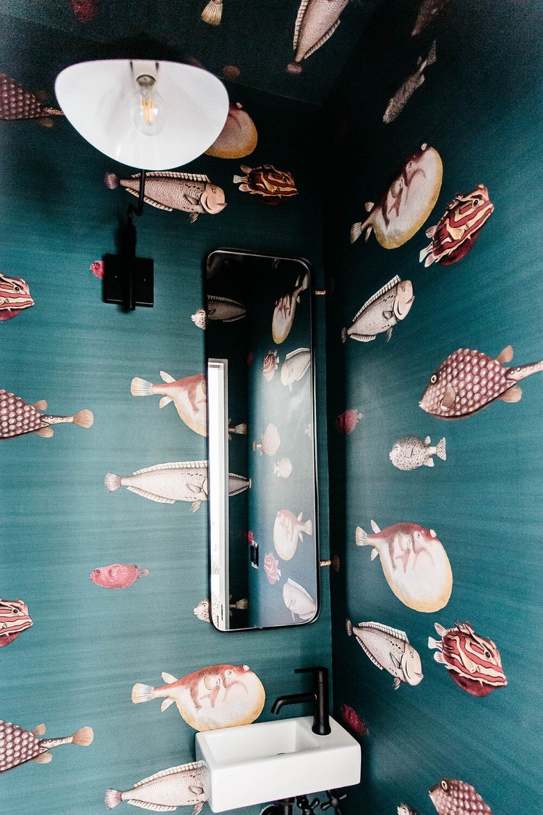 bathroom with bronze fixtures and teal wallpaper with maroon fish pattern