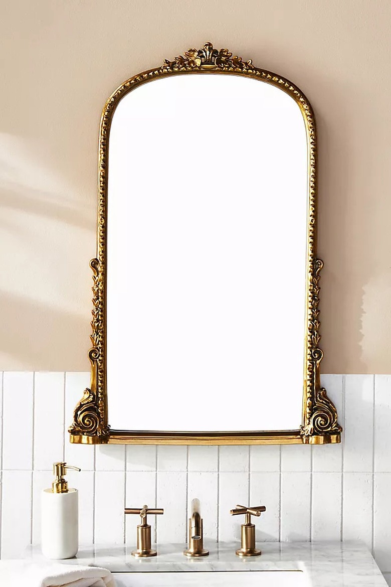 Bronze antique mirror in beige bathroom with bronze sink fixtures