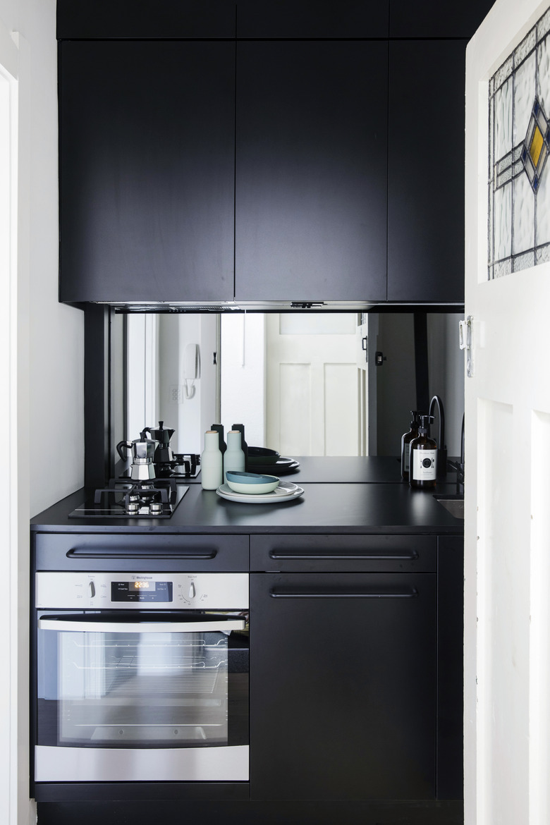 black kitchen cabinets with mirror backsplash