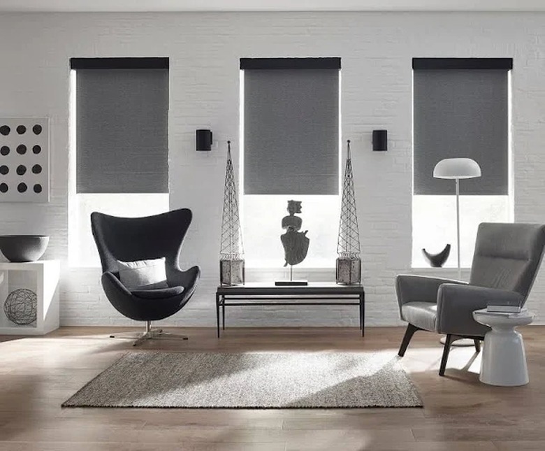 A modern living area with three windows that are covered with gray blackout shades
