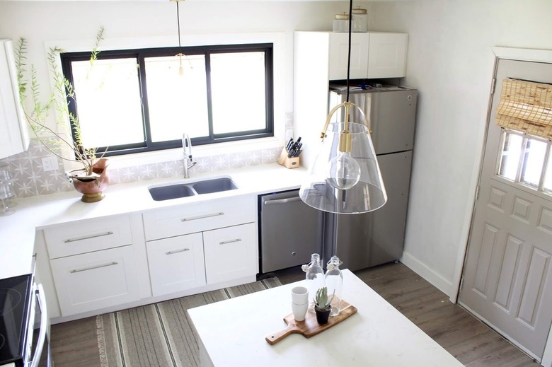 white farmhouse kitchen with gray and white tile backsplash and clear glass lights