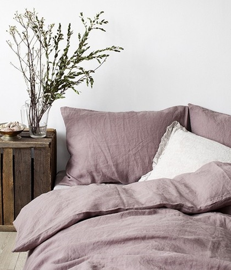 Ash-rose linen bed sheet next to a wooden night stand