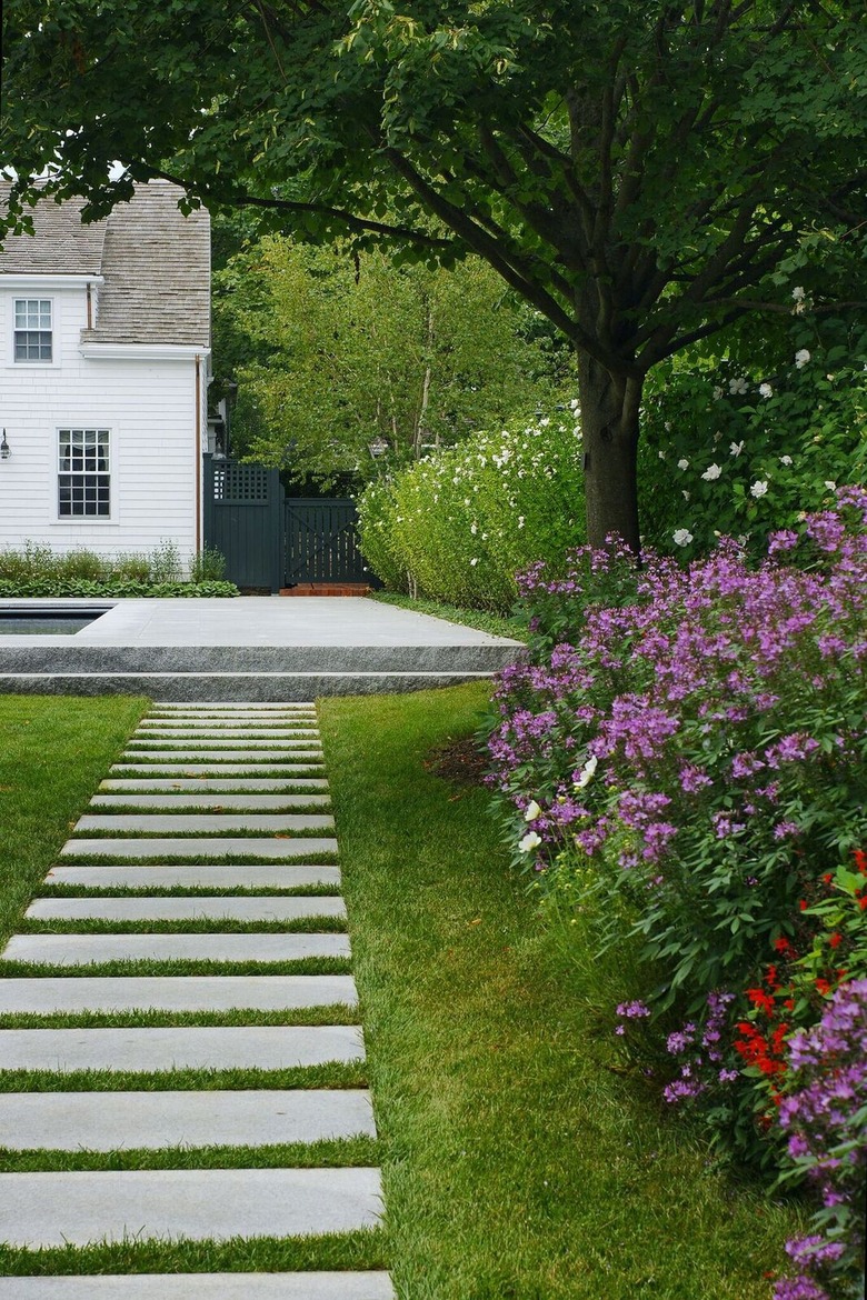 Horizontal concrete pavers are placed on a grassy path
