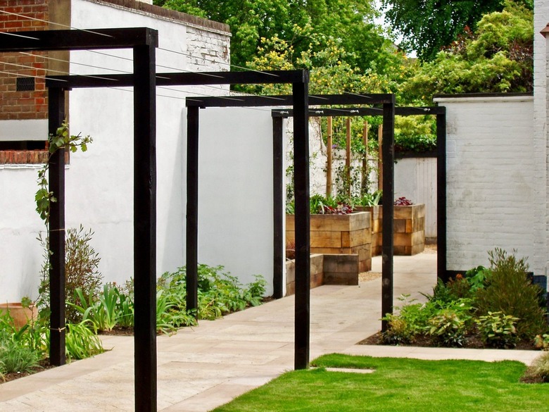 Rectangular and modern black arbors frame an entrance to a garden